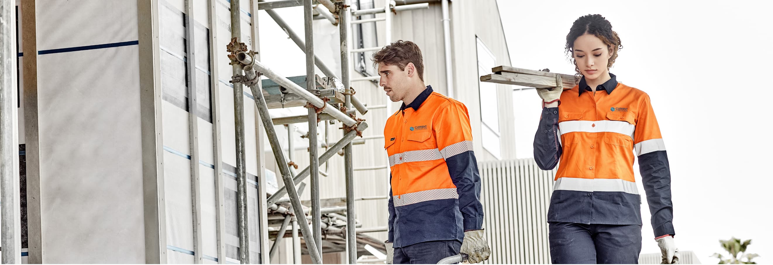 Two workers in hi-vis workwear walking across a construction site